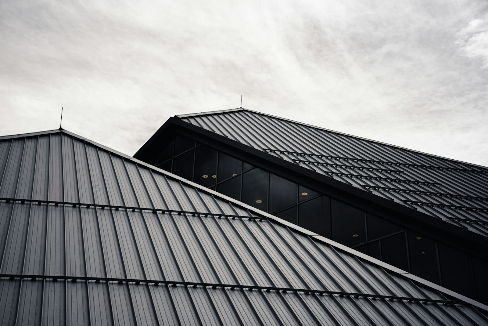 Detail of a dark standing-seam metal roof in raking light